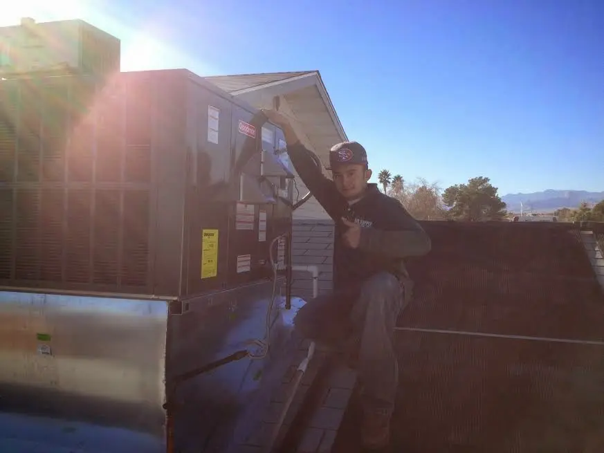 HVAC technician performing Air Duct Cleaning on a rooftop unit in Monitor